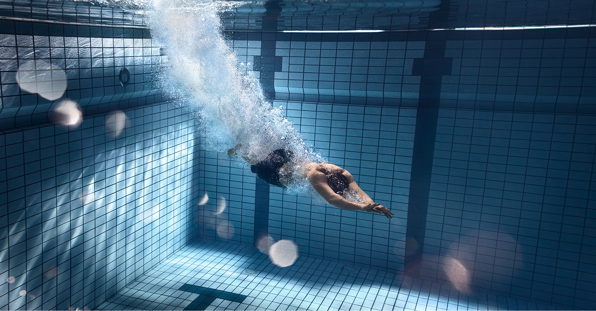 Ein Mann taucht durch ein tiefes Schwimmbecken