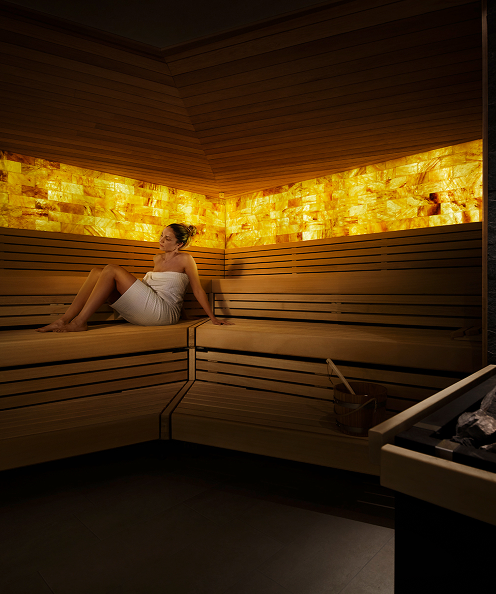 Eine nur mit Handtuch bekleidete Frau sitzt in der Salzsauna