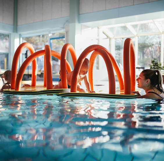 Ein Kleinkind krabbelt durch einen schwimmenden Parcours
