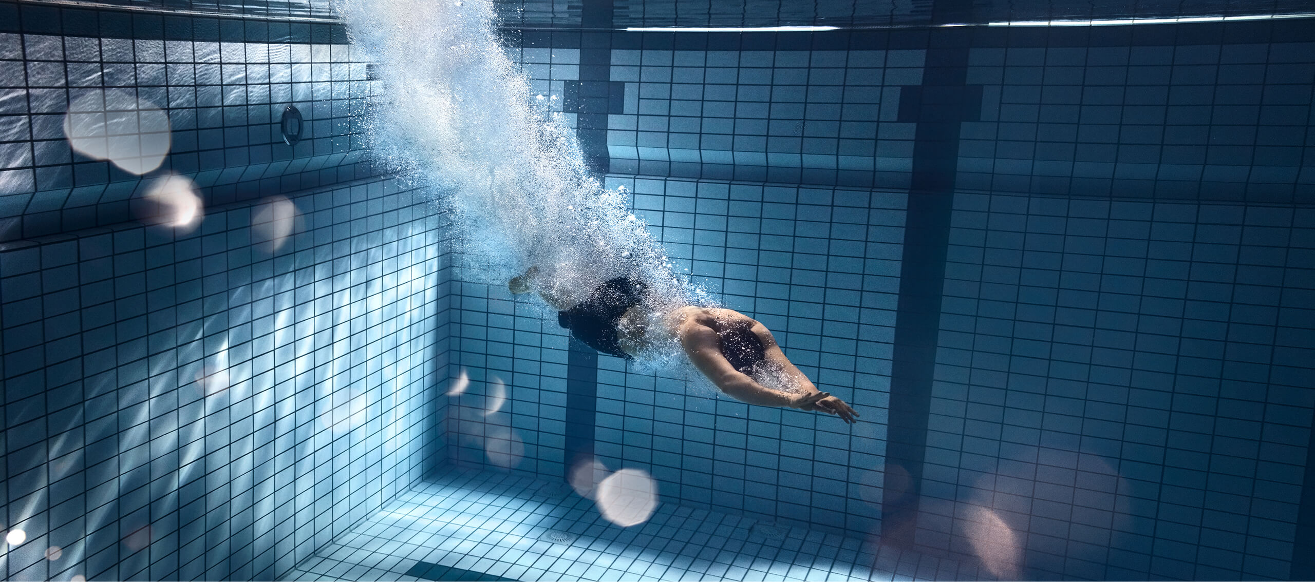 Ein Mann taucht durch ein tiefes Schwimmbecken