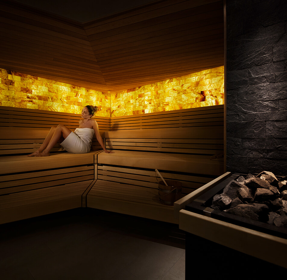 Eine nur mit Handtuch bekleidete Frau sitzt in der Salzsauna