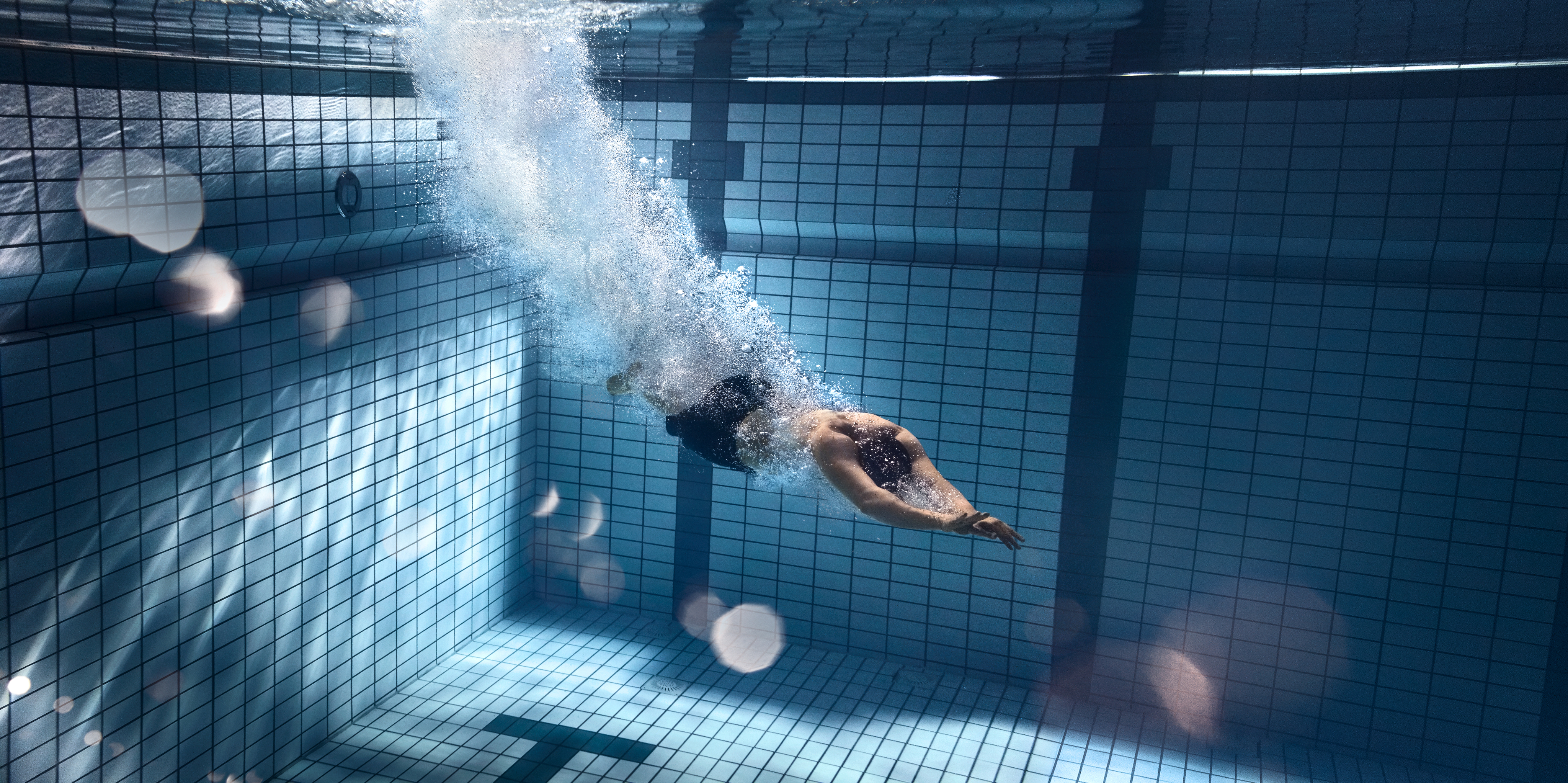 Ein Mann taucht durch ein tiefes Schwimmbecken