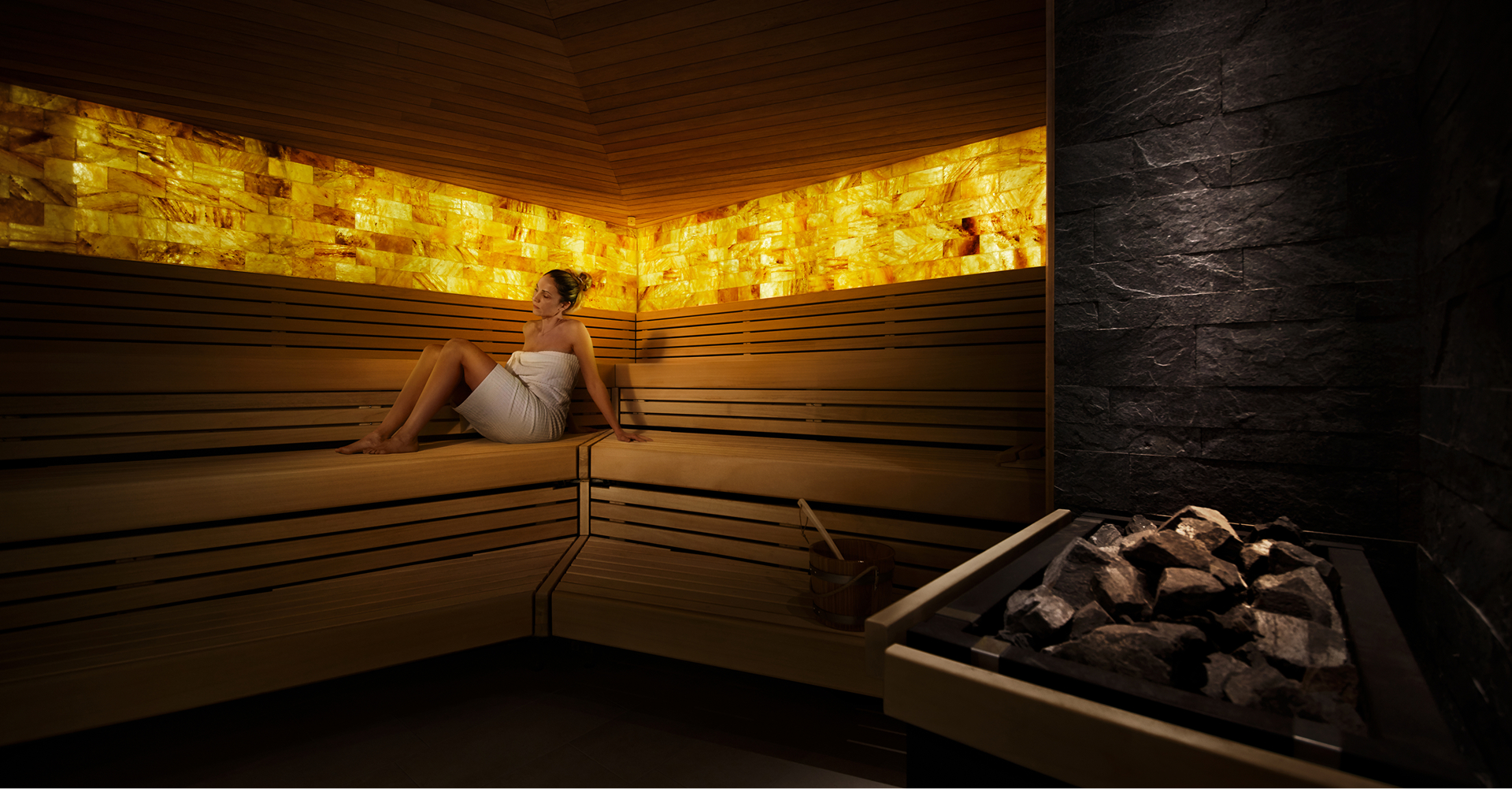 Eine Frau, nur mit einem Handtuch bekleidet, sitzt alleine in einer Sauna